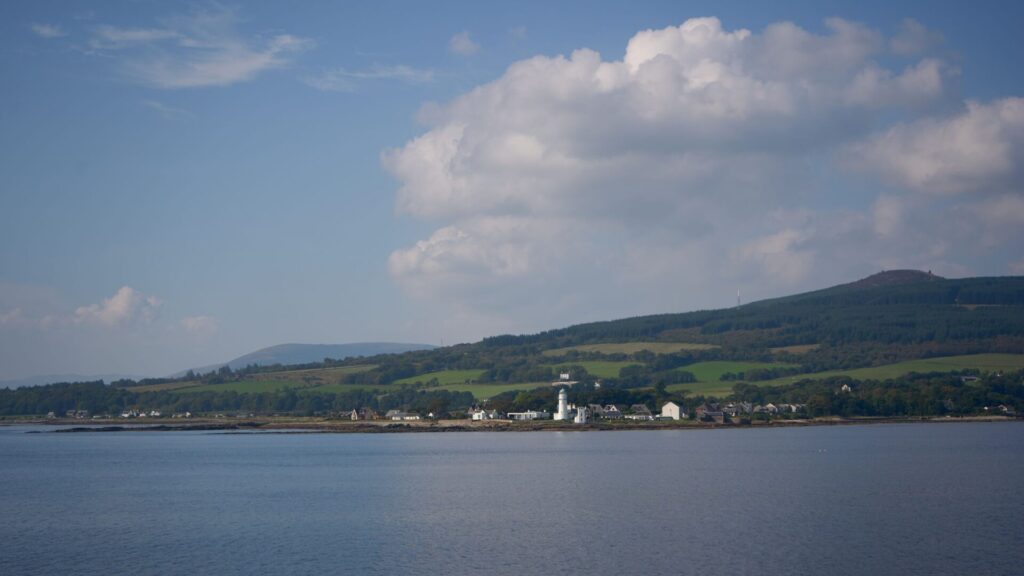 Tranquil summer landscape of the Isle of Bute in Scotland with water, hills, and village.